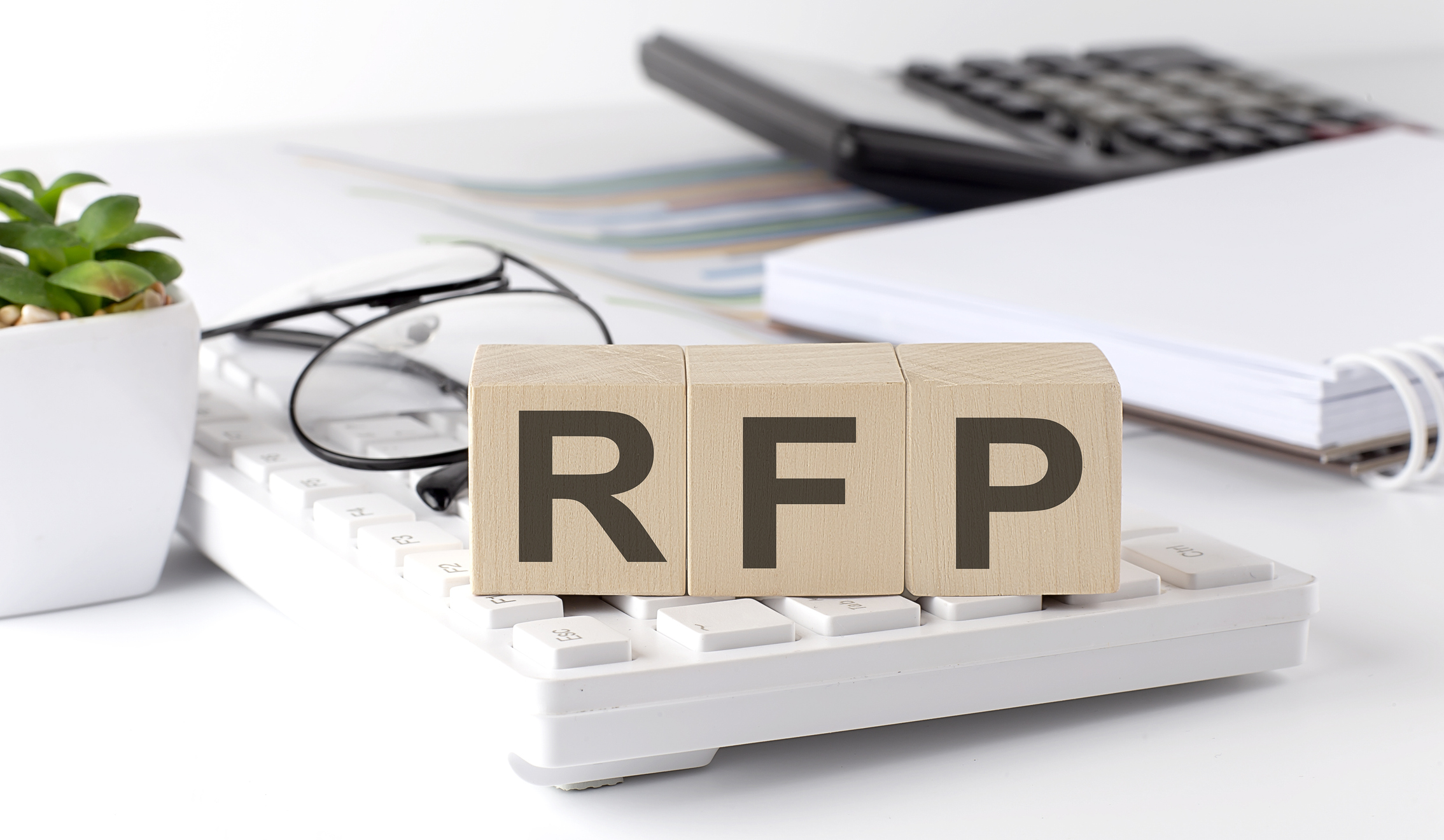 RFP written on a wooden cube on keyboard with office tools
